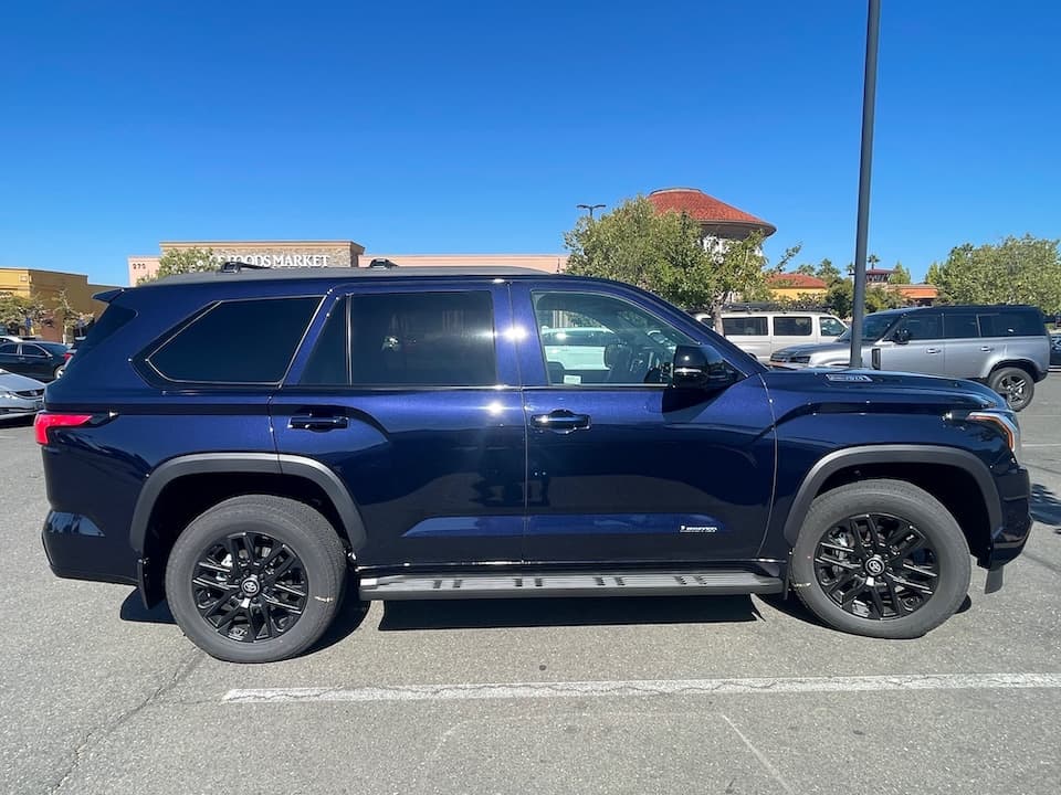 Dark blue 2026 Toyota Sequoia SUV, side profile outside a shopping center